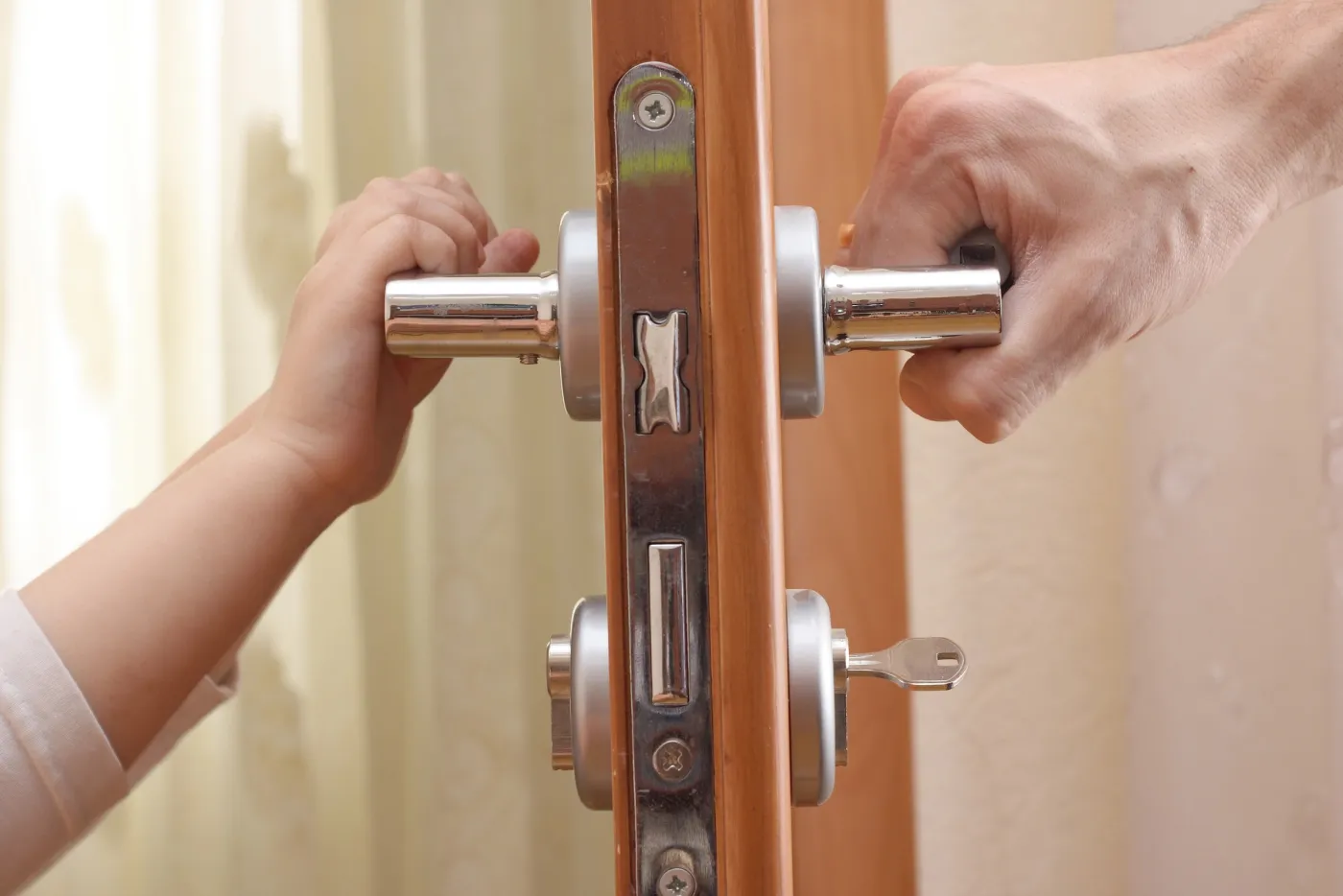 Petite main et main d'adulte sur la poignée d'une porte de maison à Bougival